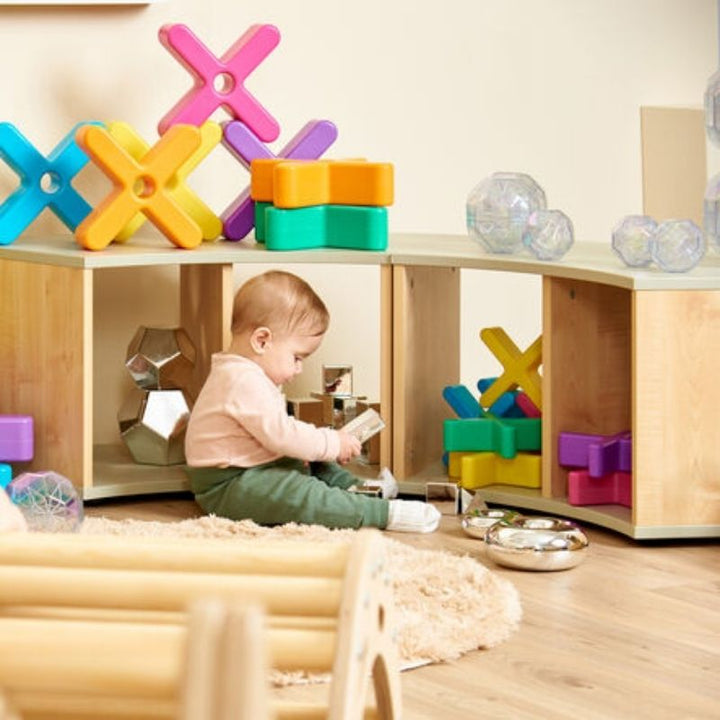 Child actively using the TTS Elements Sage Toddler Low Curved Storage Unit to access materials independently in an early years classroom