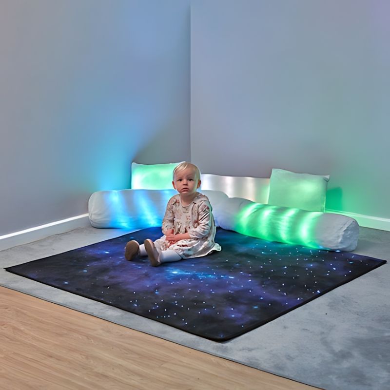 TTS Fibre Optic Sparkle Rug 100cm with a child sitting on the touch-activated surface lit in blue and green, demonstrating sensory play for therapy and home use