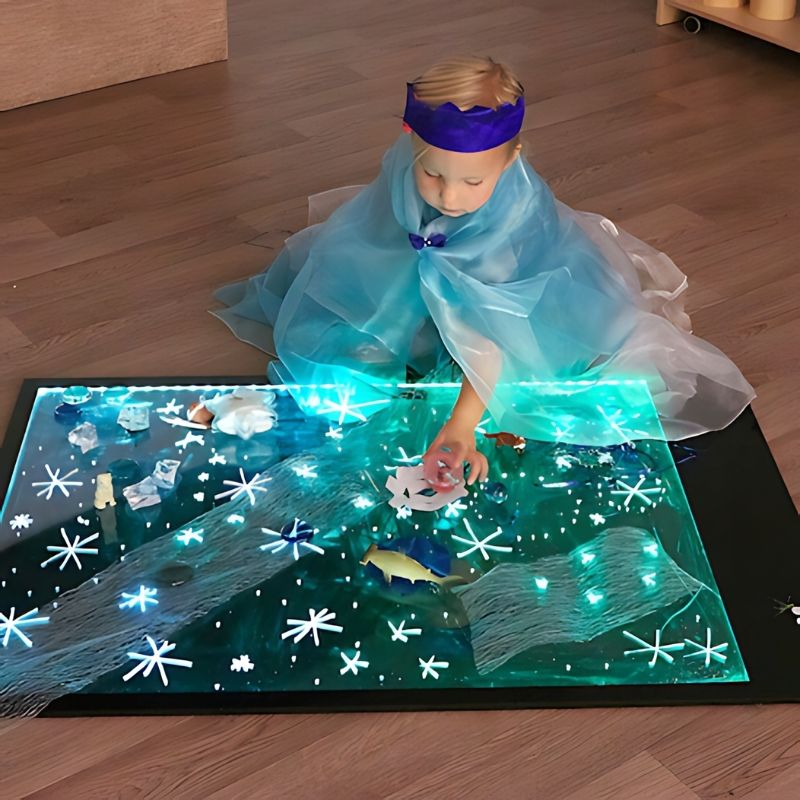 TTS Giant Illuminated Mark Making Board lit in green, showing a child engaged in mark making on the A1 light board during active floor play