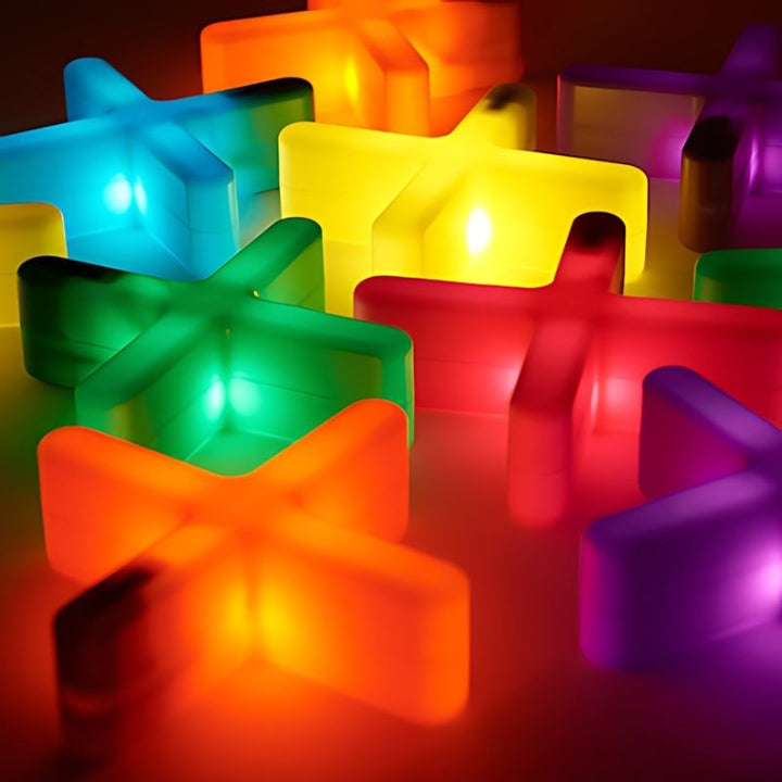 Overhead close-up of TTS Glow Crosses illuminated in red, teal, yellow, and green, highlighting the rechargeable light up feature for visual sensory exploration in early years settings