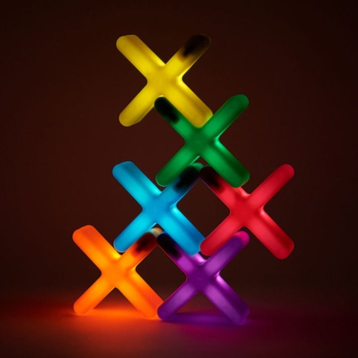TTS Glow Crosses 12-pack stacked in a rainbow tower showing all six colours - yellow, green, blue, red, orange, and purple - for sorting and sequencing sensory play