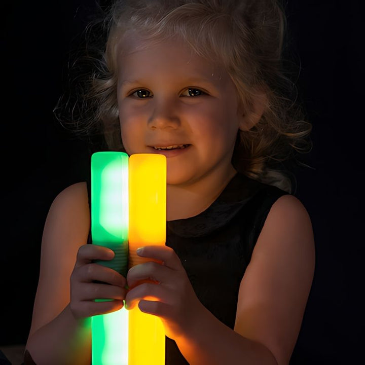 Close-up of a child's hands holding TTS Light Up Glow Cylinders, highlighting the tactile grip and LED glow that supports fine motor and visual sensory development