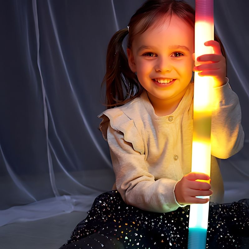 Child smiling while playing with TTS Light Up Glow Cylinders, capturing the joy and engagement of LED sensory light play for early learners