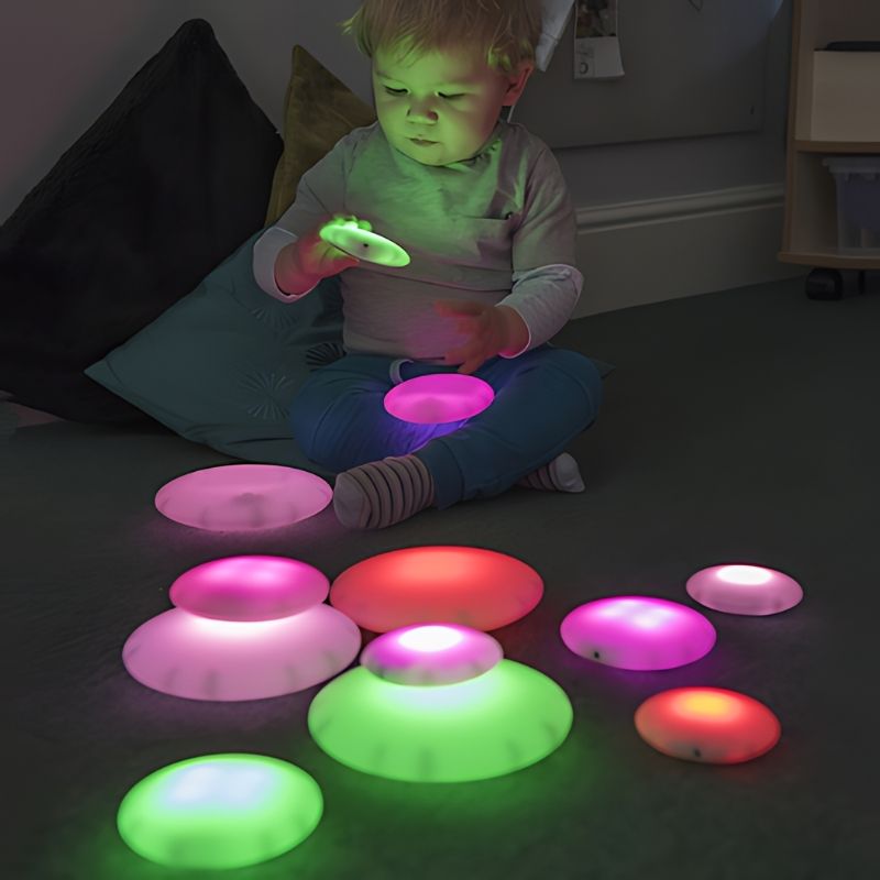 Boy rolling TTS Glow Pebbles during sensory exploration play, demonstrating schema play and spatial reasoning development