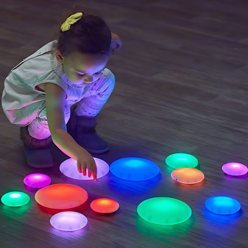 Child playing with TTS Glow Pebbles rechargeable LED sensory pebbles, exploring colour and light through hands-on tactile play