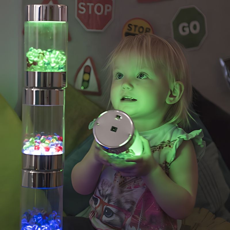 Child playing with a pile of TTS Illuminated Glow Roller Shakers, exploring stacking and schema play with rechargeable sensory light toys
