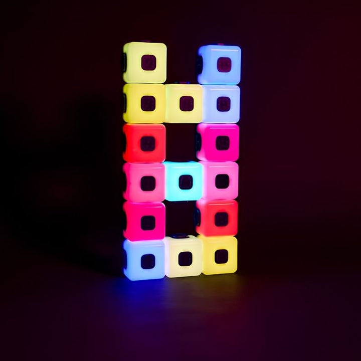 TTS Glow Sequencing Cubes arranged in a two-column tower against a dark background, displaying a repeating colour sequence pattern in yellow, white, pink, cyan and red