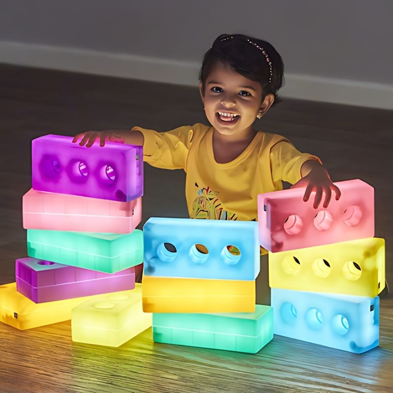 TTS Light Up Glow Construction Bricks with a child's hands actively tapping and exploring the rechargeable sensory bricks during tactile play