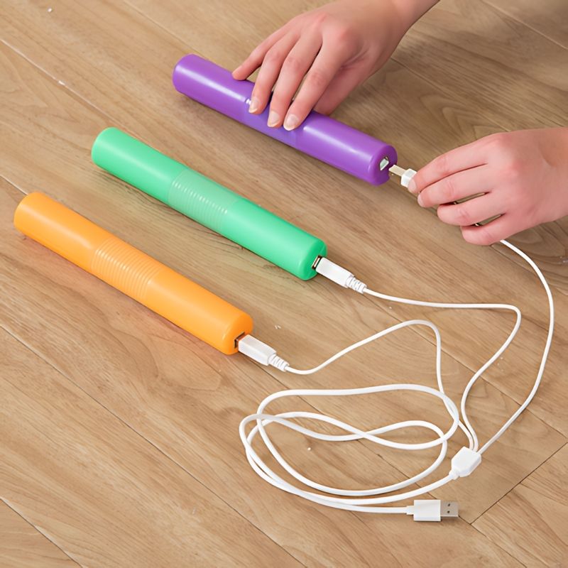 TTS Light Up Glow Cylinders set charging via included USB cable, demonstrating the rechargeable design that supports ongoing classroom and therapy use