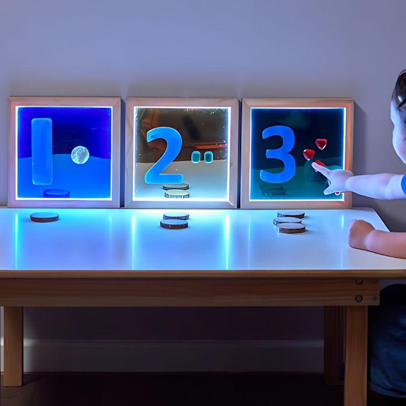 TTS Light Up Hand Held Mirrors 3pk displayed front-on showing three illuminated acrylic mirrors in blue, green, and gold for sensory play and early years learning