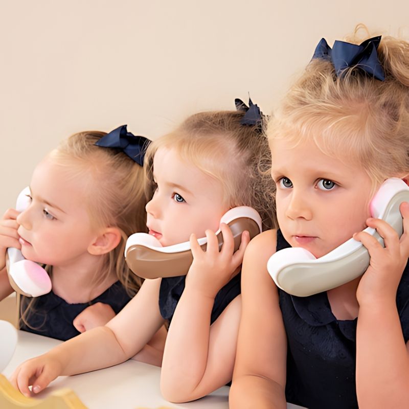 Three children using TTS Light Up Phones during role play, supporting communication skills and turn-taking in an early years setting