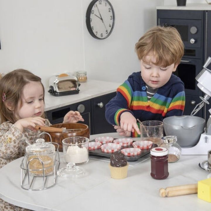Two children engaged in collaborative pretend baking at the TTS Modern Living Kitchen Island Set, developing communication skills and fine motor development through dramatic play