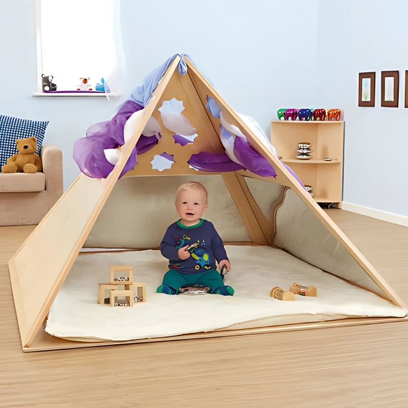 Toddler boy playing inside the TTS Wooden Pyramid Den, an early years wooden den designed for calm corners, imaginative play, and sensory learning