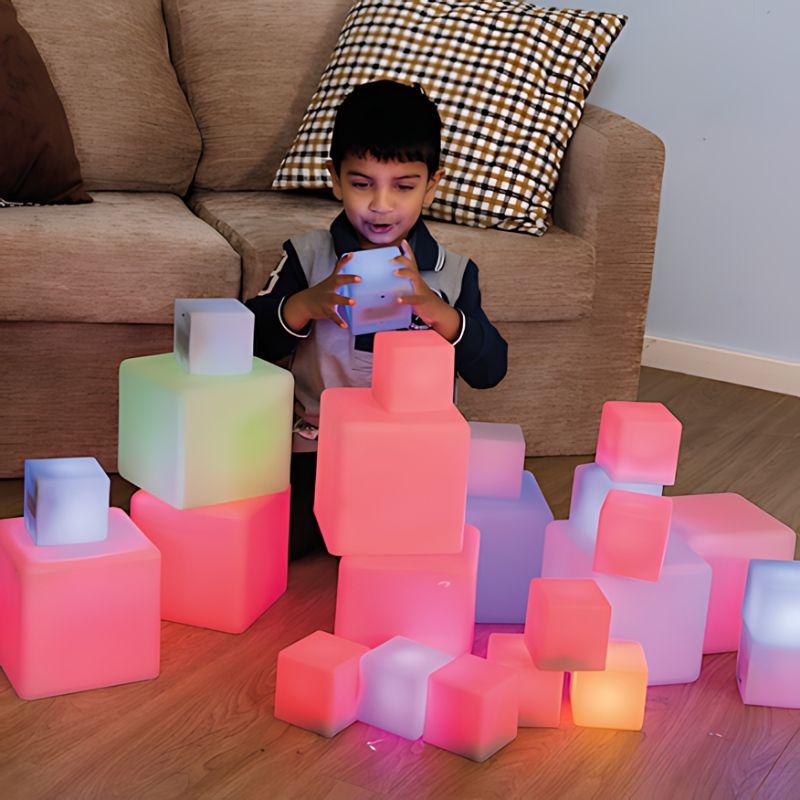 TTS Sensory Glow Construction Blocks in a landscape view with a child actively exploring the colour-changing light up cubes during early years play