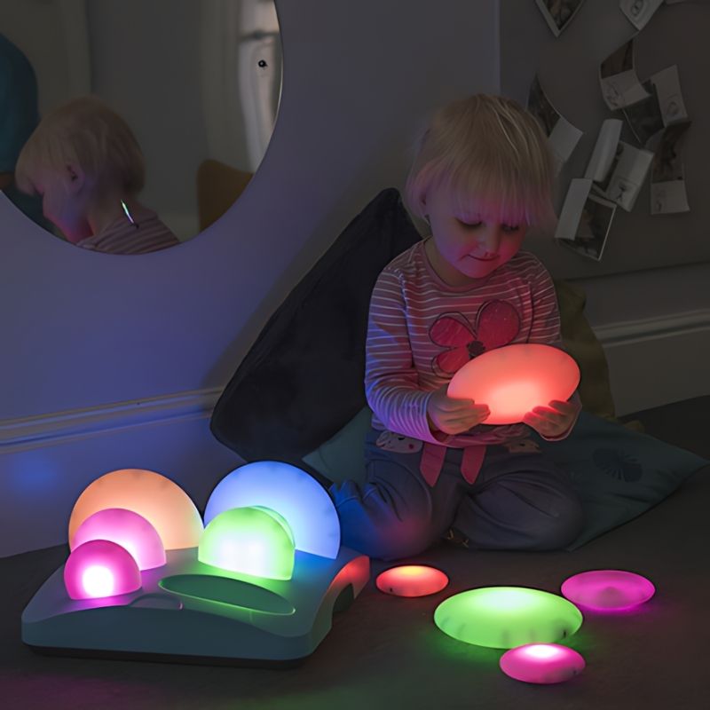 Girl seated and actively exploring TTS Sensory ICT Glow Set components, demonstrating tactile and visual sensory engagement for early years learners