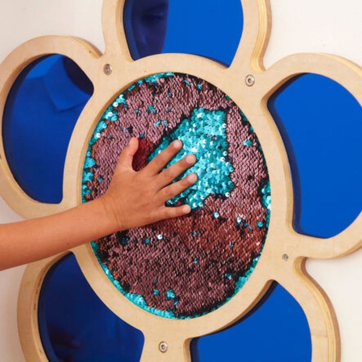 Hand interacting with TTS blue Mark Making Sequin Daisy Frame, showing mermaid sequin texture and tactile sensory engagement - fine motor sensory wall panel