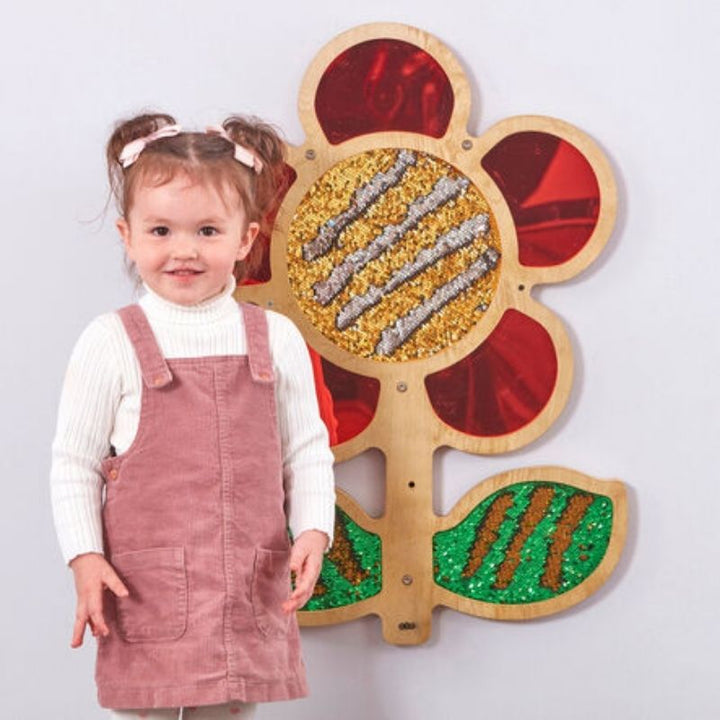 TTS red sequin daisy frame mounted on wall with a child interacting with the tactile sequin surface - sensory wall panel for classrooms and therapy rooms