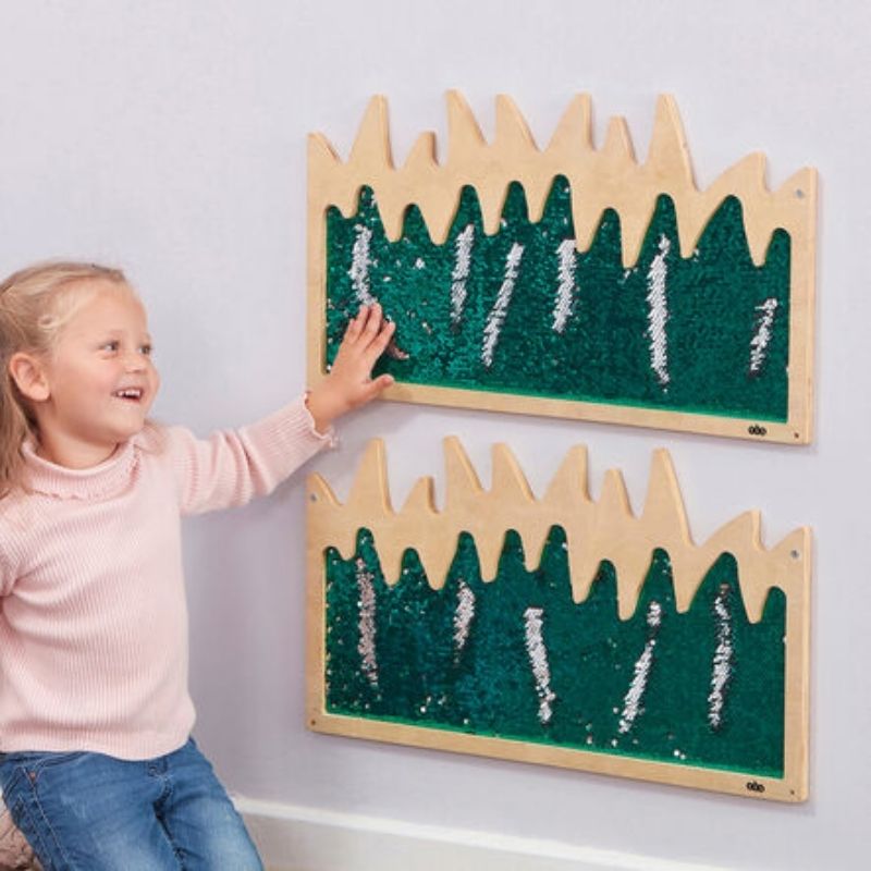 Girl using the TTS Mark Making Sequin Grass Boards, running her fingers across the flip sequin surface to create patterns - a tactile sensory wall panel for classrooms and play spaces
