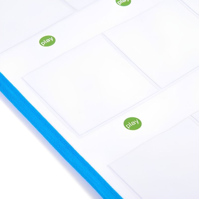 Angled close-up of the TTS Interactive Talking Mat surface showing clear card pockets, green play buttons and the durable blue fabric binding edge