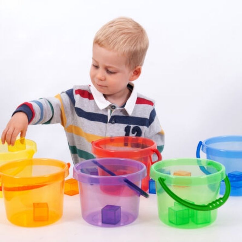 Young boy engaged in sensory sand and water play with TTS Translucent Colour Buckets, building fine motor skills and colour recognition through hands-on exploration