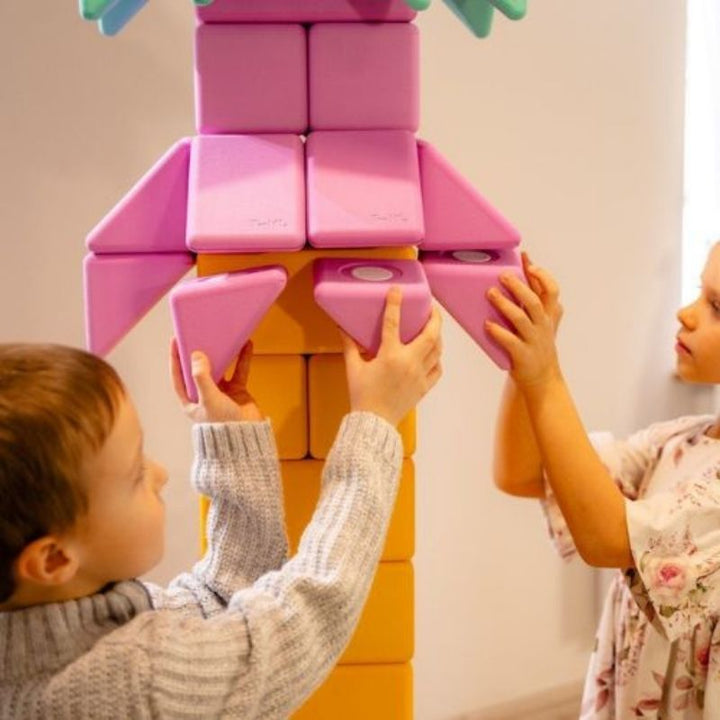 Two children collaboratively building a floor-scale structure with the TUKI BIG Magnetic Blocks Builder 150, showing the voluntary pair construction dynamic that block abundance at 150 pieces enables within a larger group session