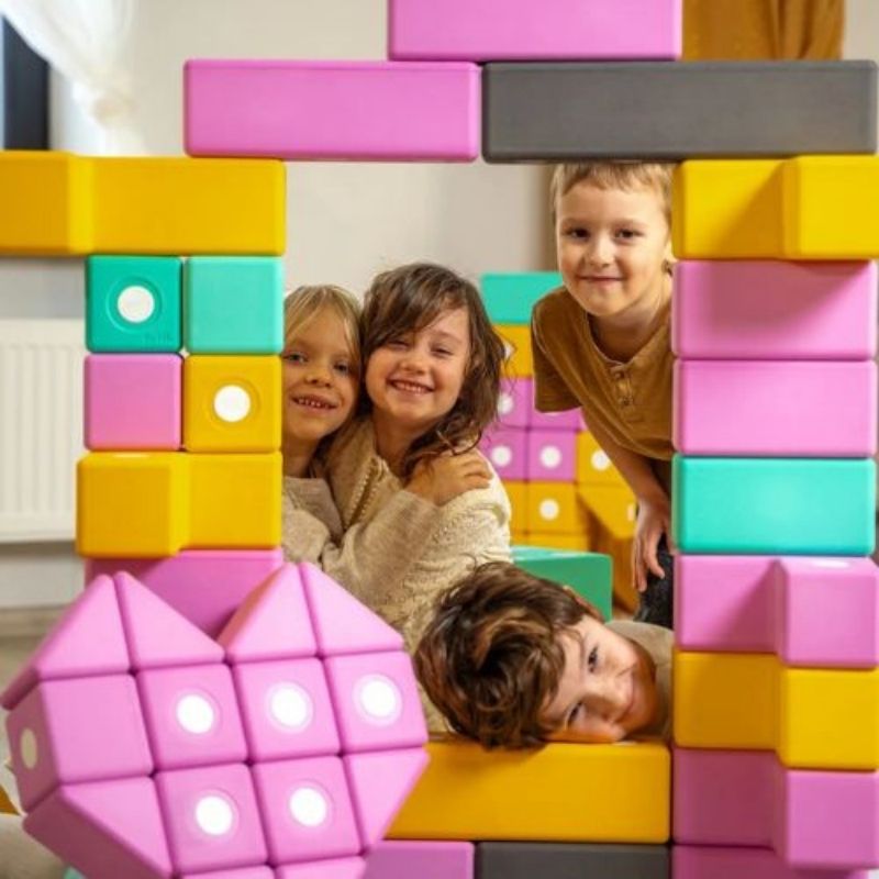 Four children simultaneously building a floor-scale structure with the TUKI BIG Magnetic Blocks Builder 56, demonstrating the 3-5 child group construction capacity of the 56-piece EN71-certified large-format magnetic foam block set