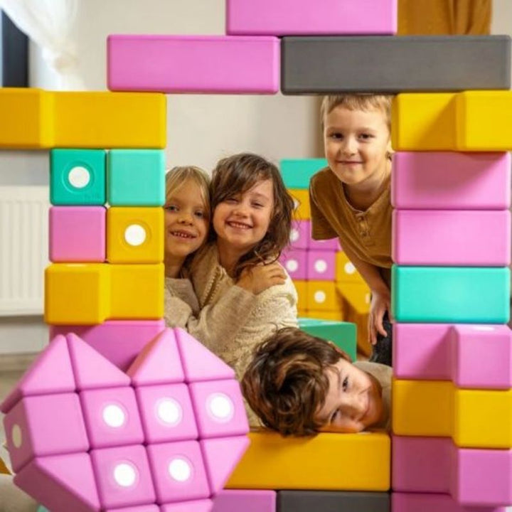 Four children simultaneously building a floor-scale structure with the TUKI BIG Magnetic Blocks Builder 56, demonstrating the 3-5 child group construction capacity of the 56-piece EN71-certified large-format magnetic foam block set