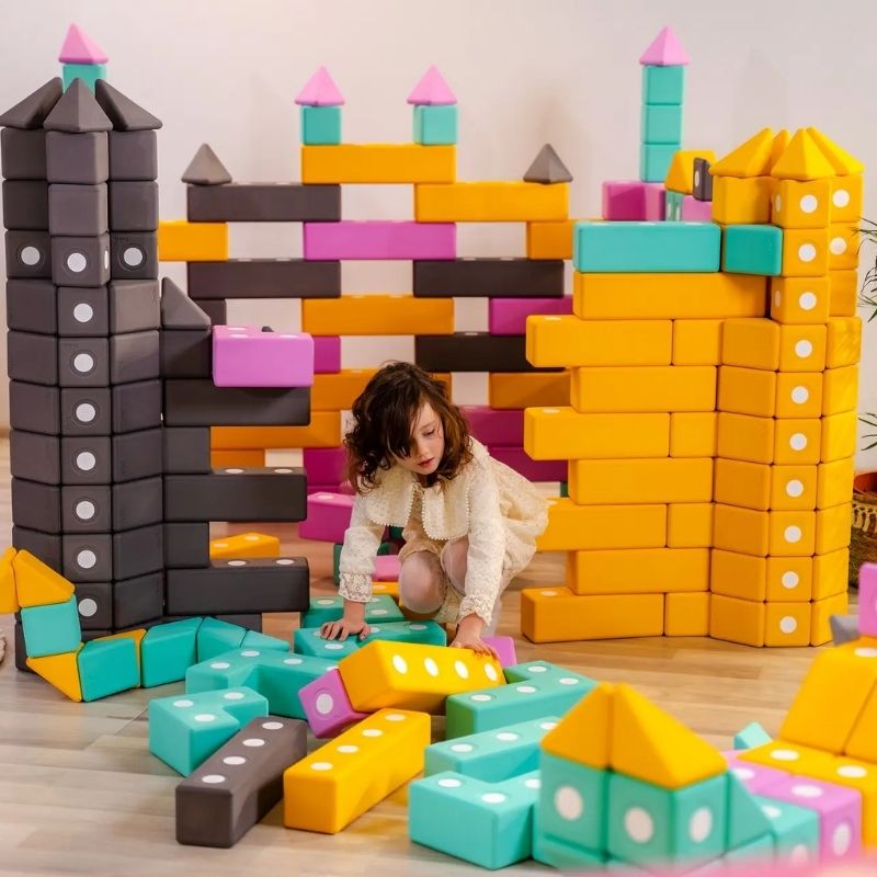 Child actively building with TUKI Big Magnetic Foam Blocks Smart 280, showing open-ended sensory and fine motor play with large-format magnetic foam blocks