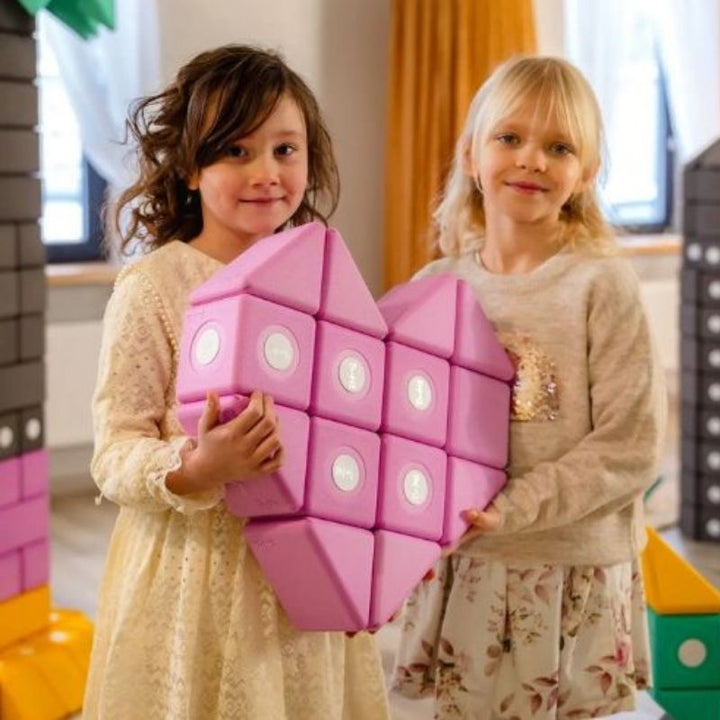 Two girls building a heart figure with the TUKI BIG Smart Magnetic Blocks Smart 10 set, showing the creative imaginative construction the 3 Smart TUKI shapes including pyramid enable for individual and pair play