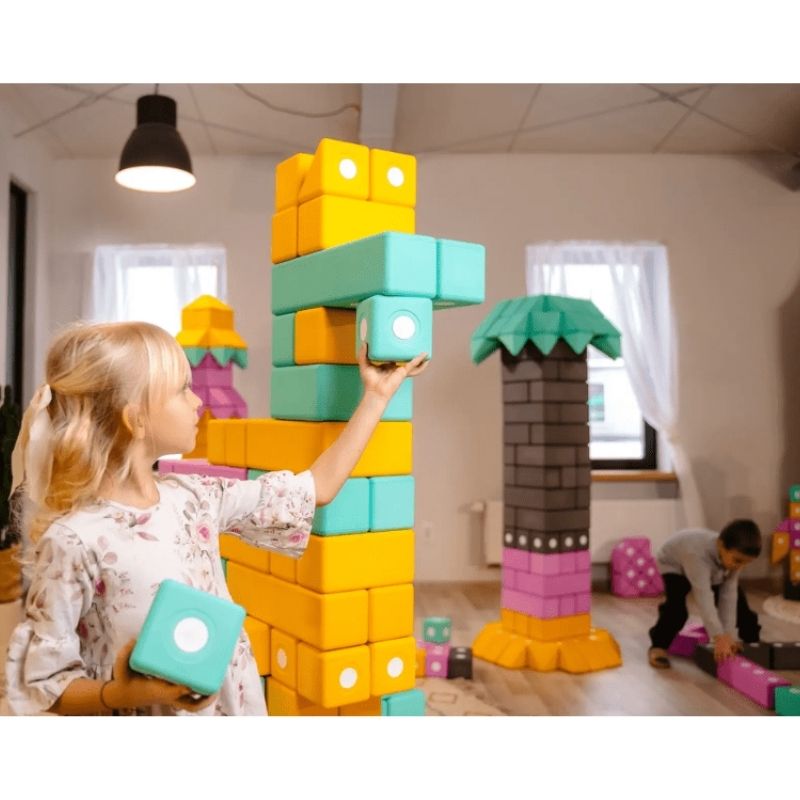 Two children building a landscape-view floor-scale structure with the TUKI BIG Smart Magnetic Blocks Smart 75, demonstrating the paired construction the 75-piece 3 Smart shapes 4-colour set supports within a group of 4-6 children