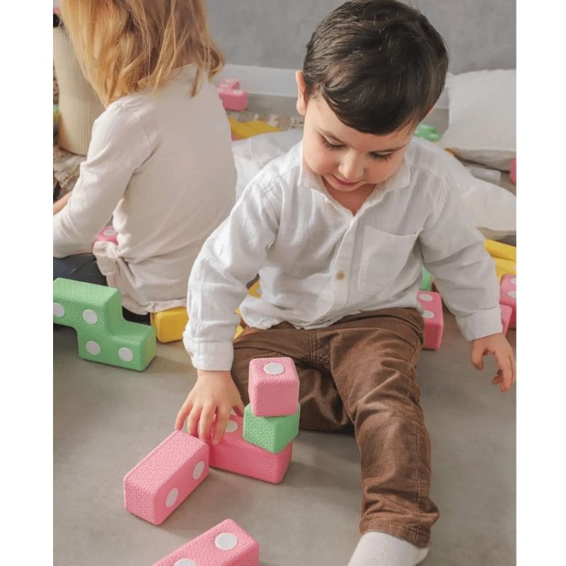 Child actively playing with the TUKI Regular Magnetic Blocks 26 Elements set, demonstrating open-ended magnetic foam block construction and tactile sensory play