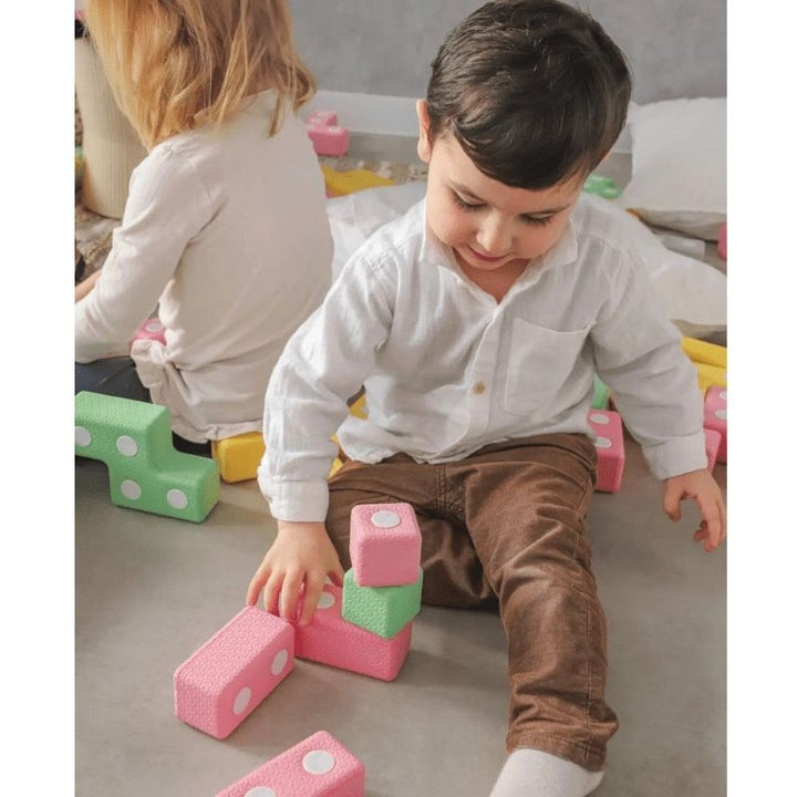 Child actively playing with the TUKI Regular Magnetic Blocks 26 Elements set, demonstrating open-ended magnetic foam block construction and tactile sensory play