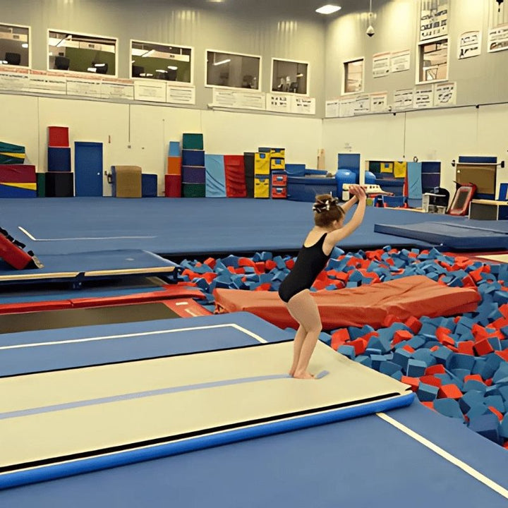 Girl actively tumbling or performing gymnastics on the Tumbl Trak Air Floor in Blue, demonstrating the bouncy inflatable surface that provides more responsive rebound than a traditional spring floor for skill training