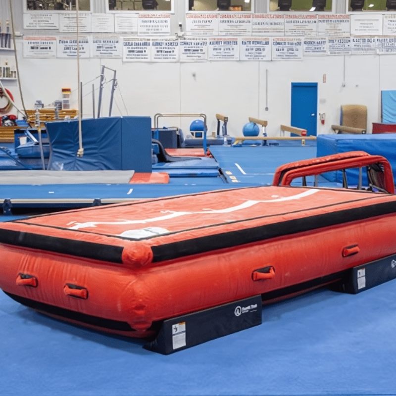 Tumbl Trak Air Platform Mat corner view in an indoor gym or therapy space showing the full inflated height and non-skid perimeter base for use as a vault station or sensory play platform