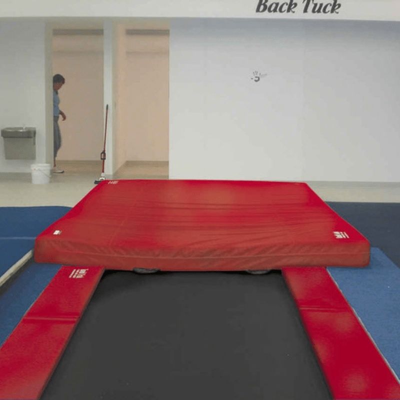 Front view of the Tumbl Trak Inground Tumbling Track in red colourway showing the flush floor installation profile and pad system for gymnastics club facilities