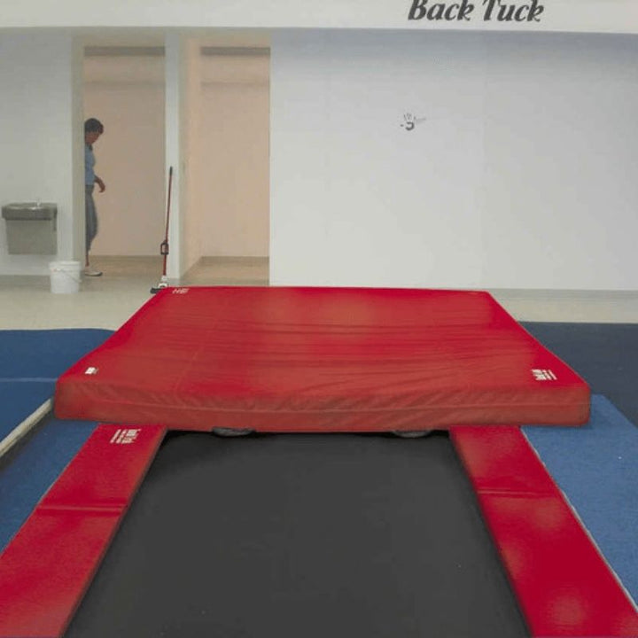 Front view of the Tumbl Trak Inground Tumbling Track in red colourway showing the flush floor installation profile and pad system for gymnastics club facilities