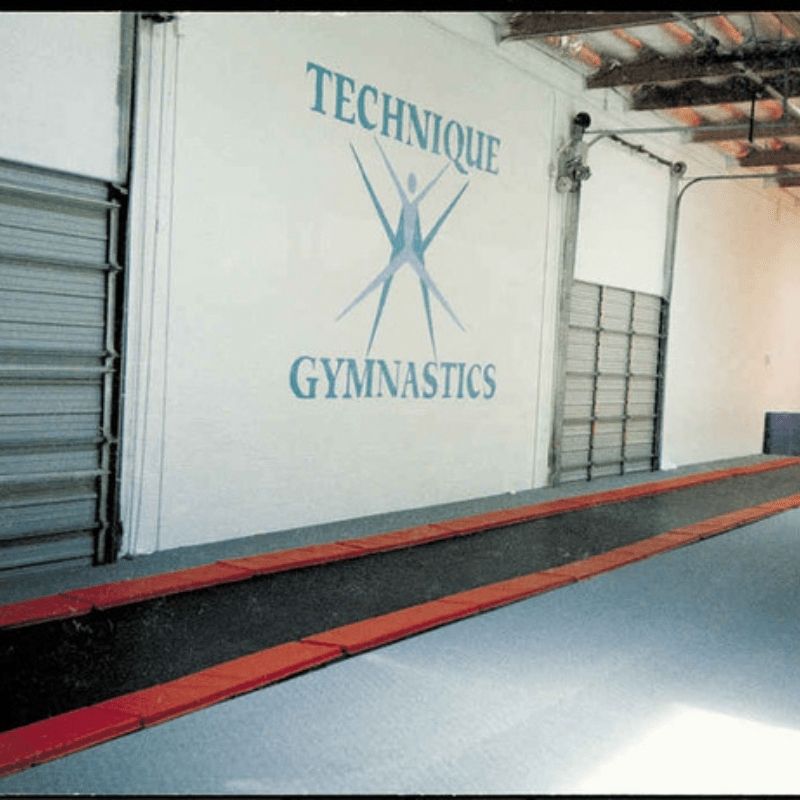 Tumbl Trak Inground Tumbling Track in an indoor gymnastics facility showing the seamless flush-floor installation and continuous tumbling surface for elite and recreational athlete training