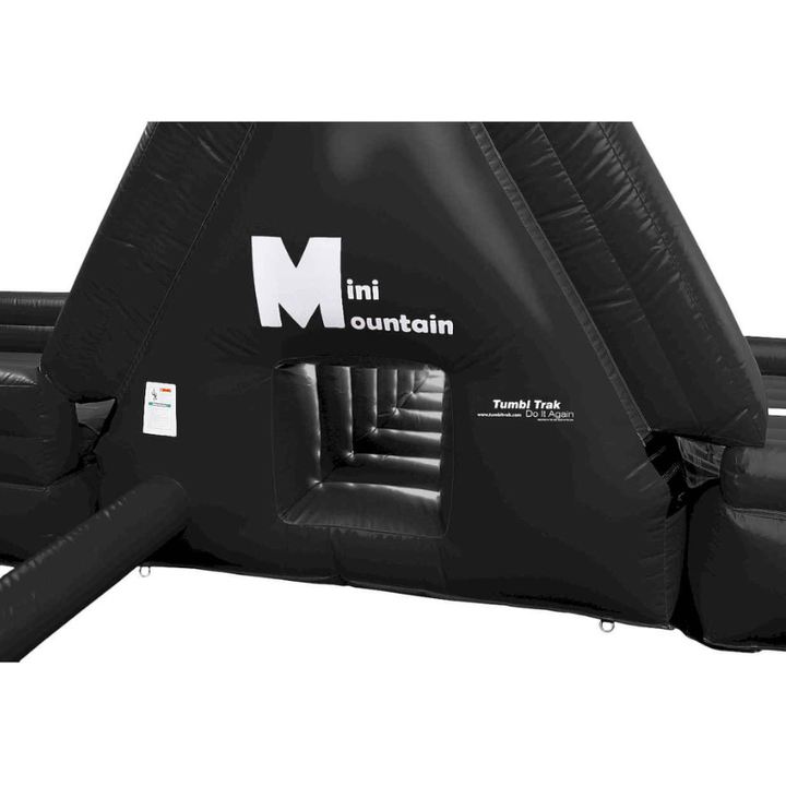 Tumbl Trak Mini Mountain black variant clean view showing the 9-foot-wide inflatable constant-flow play station with D-ring bottom corners, Velcro end flap, and built-in cargo net and climbing rope for indoor gymnasium use