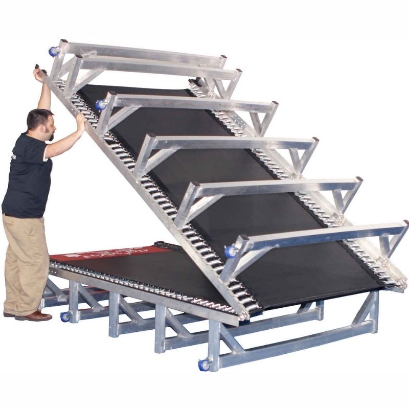 Adult folding the Tumbl Trak Porta Trak demonstrating the no-tools folding system that reduces the 15ft or 20ft foldable aluminium gymnastics track to half its length for wheeled storage in small gym clubs and mobile programmes