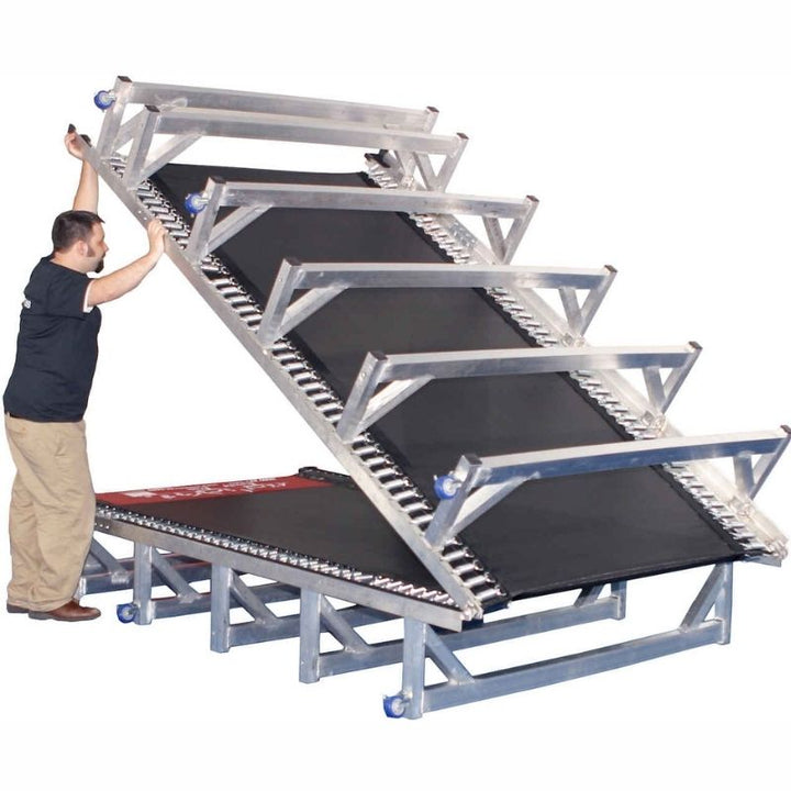 Adult folding the Tumbl Trak Porta Trak demonstrating the no-tools folding system that reduces the 15ft or 20ft foldable aluminium gymnastics track to half its length for wheeled storage in small gym clubs and mobile programmes