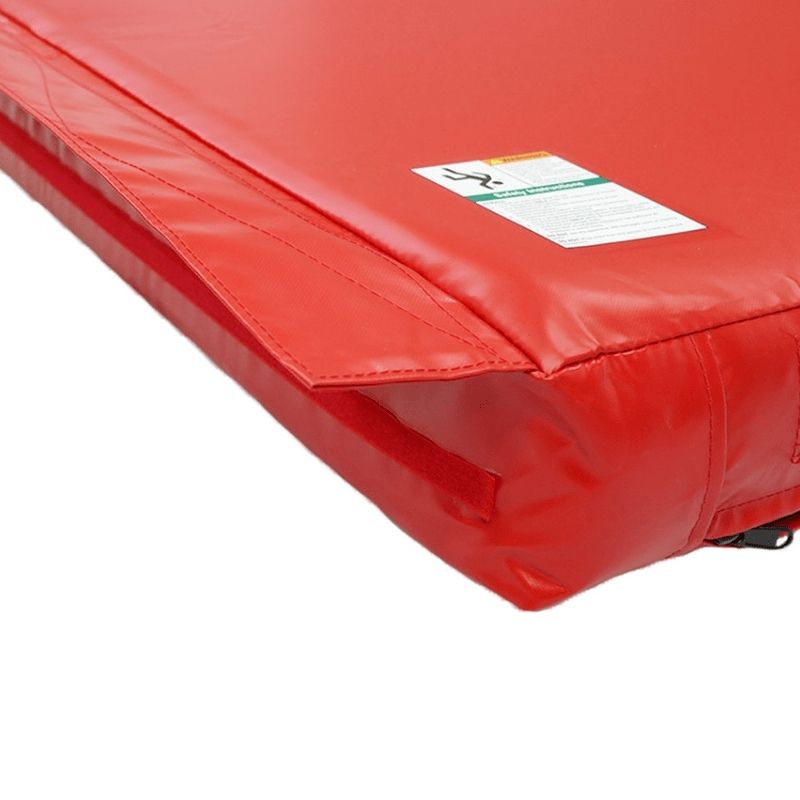 Corner view of the Tumbl Trak Practice Mat showing the 18 oz. knife-coated vinyl surface, Dacron thread seam stitching, and 2-inch nylon web strap construction that provides commercial-grade durability for daily gymnastics training use