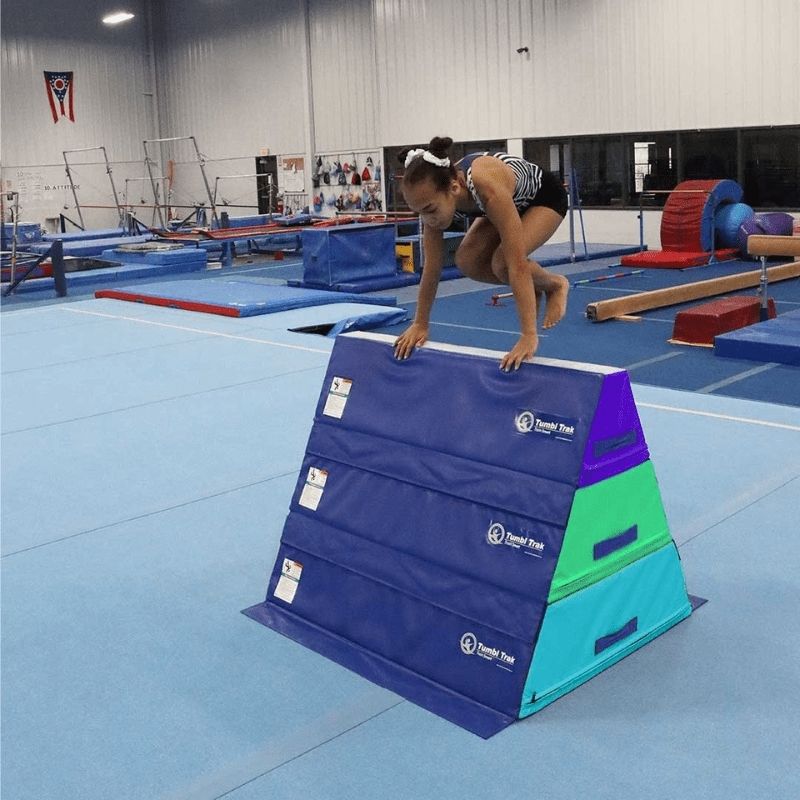 Girl hopping across the Tumbl Trak Pyramid Beam Blocks end-to-end progressive beam configuration, demonstrating gross motor coordination, motor planning, and balance development through gymnastics beam training and obstacle course activities