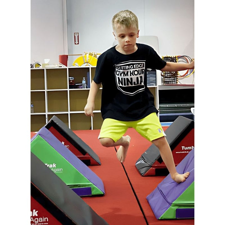 Child actively using the Tumbl Trak Slanted Ninja Steps from a front view, demonstrating agility, balance, and proprioceptive gross motor development during indoor ninja obstacle course training