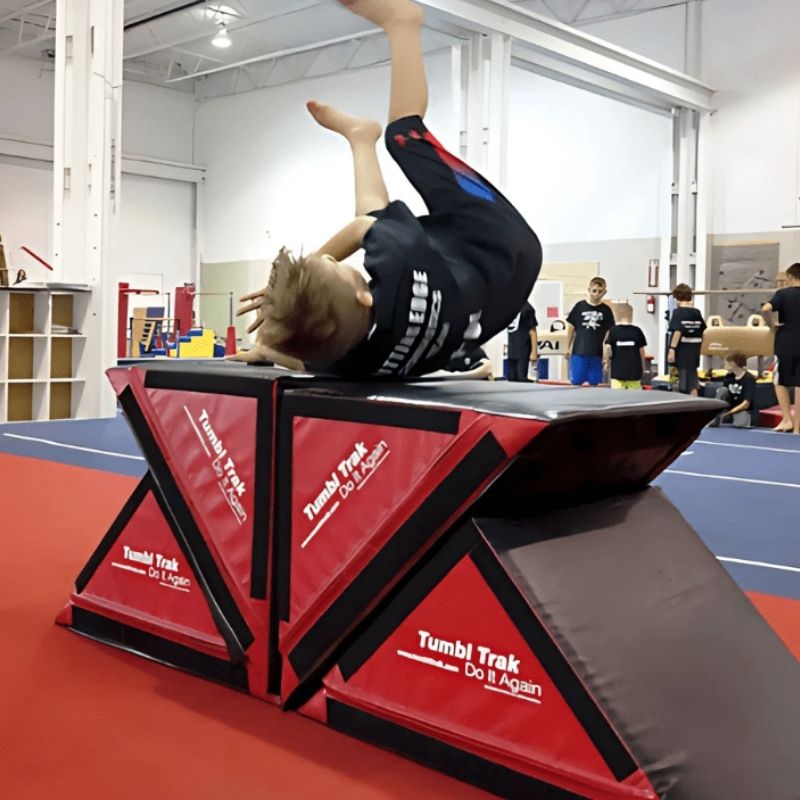 Boy tumbling across the Tumbl Trak Slanted Ninja Steps showing the firm yet forgiving crosslink foam surface supporting gymnastics skills, motor planning, and active movement training indoors