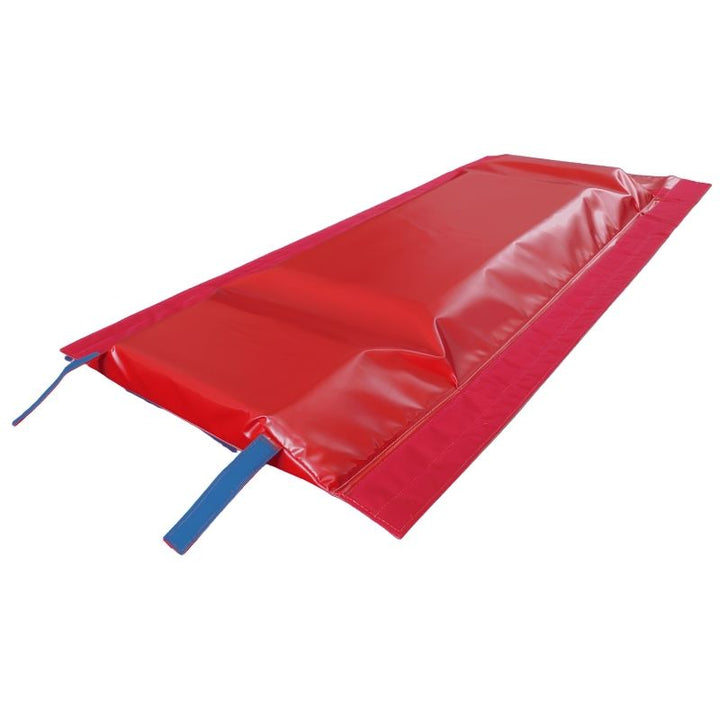 Underside of the Tumbl Trak T-Trainer Cover PRO showing the red vinyl base, trampoline bed contact window, and blue Velcro straps used to secure the vault trainer topper