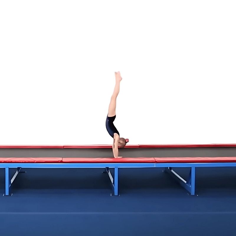 Young female gymnast performing a handstand on the Tumbl Trak tumbling track, demonstrating the high-tension spring bed surface used for skill repetition and vestibular motor development