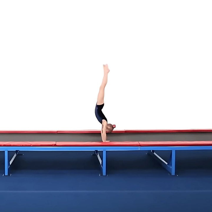 Young female gymnast performing a handstand on the Tumbl Trak tumbling track, demonstrating the high-tension spring bed surface used for skill repetition and vestibular motor development