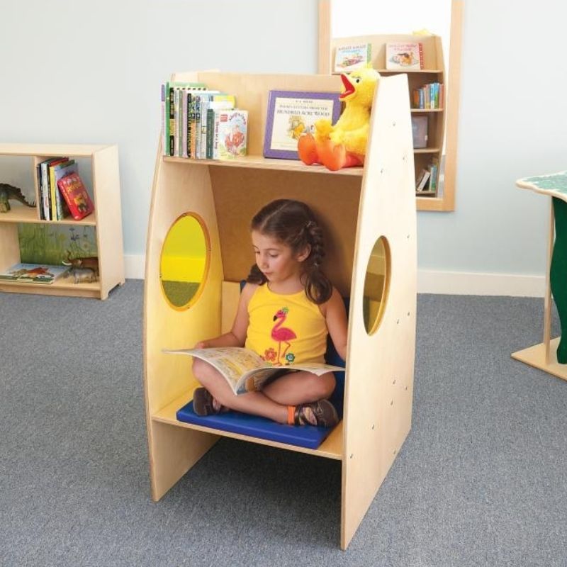 Child reading inside the Whitney Brothers Alone Zone private reading chair, showing the enclosed structure, yellow acrylic side windows, and cosy interior of the classroom quiet space chair
