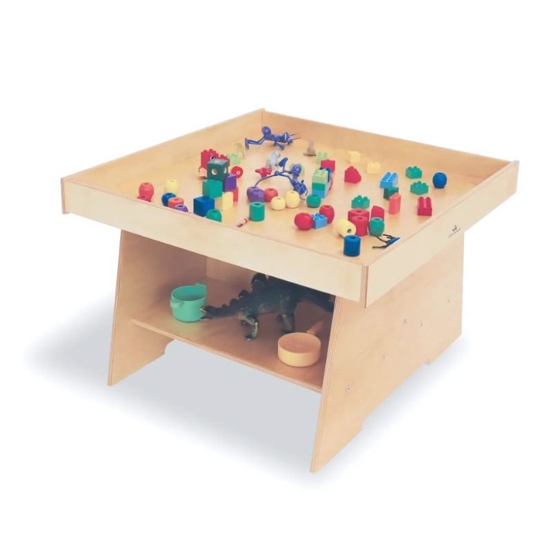 Front view of the Whitney Brothers Big Wide Discovery Table with toys, showing the 31" wide birch plywood activity surface with full-perimeter lip for toddler and first walker play
