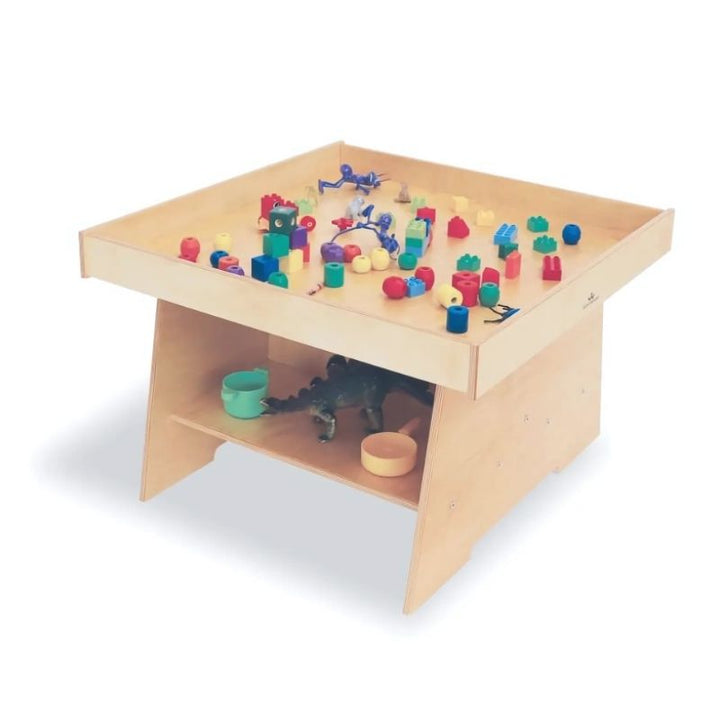 Front view of the Whitney Brothers Big Wide Discovery Table with toys, showing the 31" wide birch plywood activity surface with full-perimeter lip for toddler and first walker play